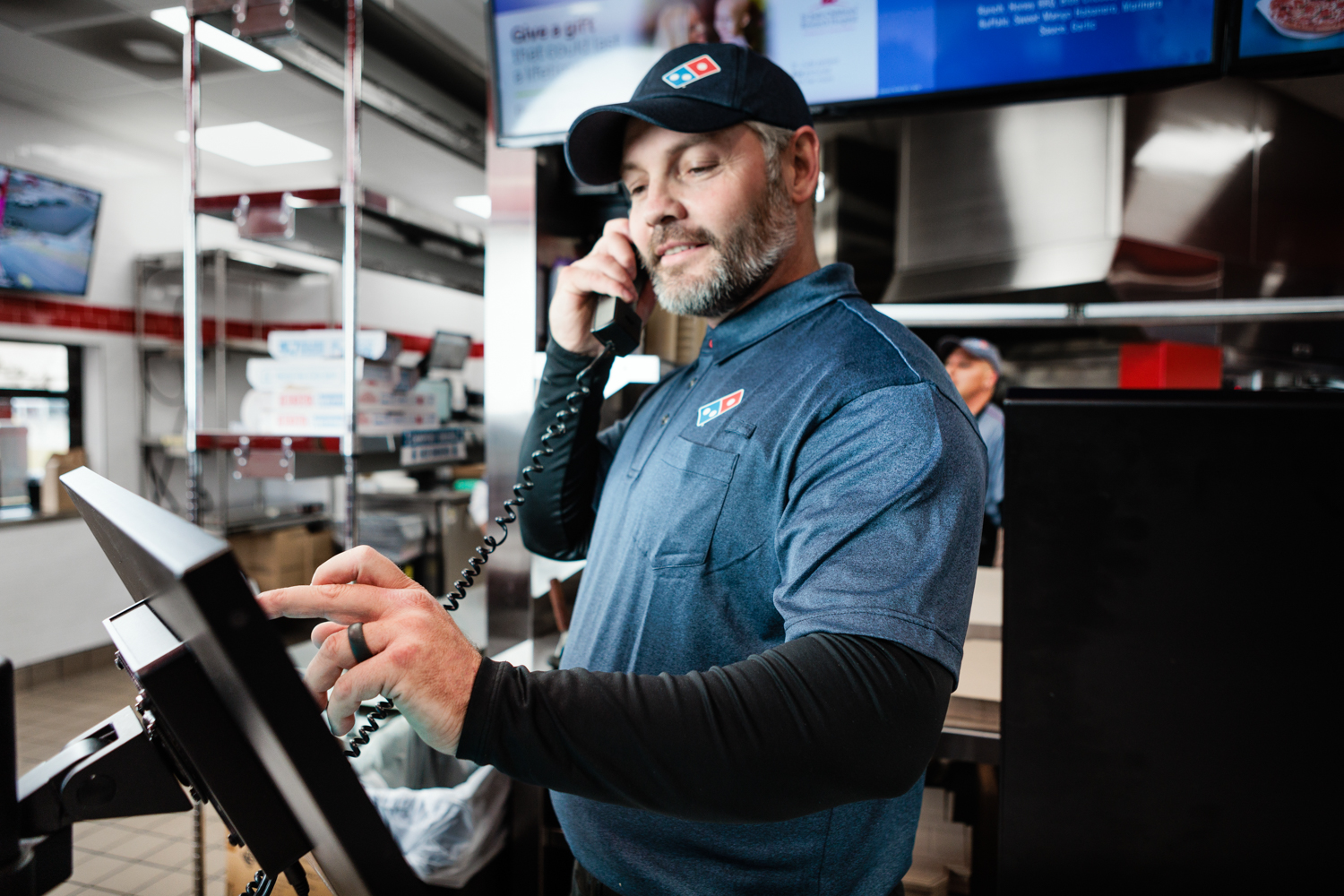 a man in a blue shirt and hat talking on a phone