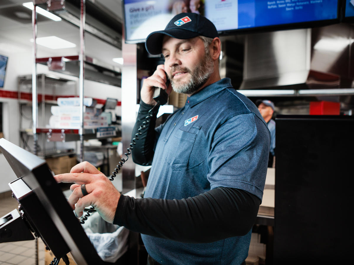 a man in a blue shirt and hat talking on a phone