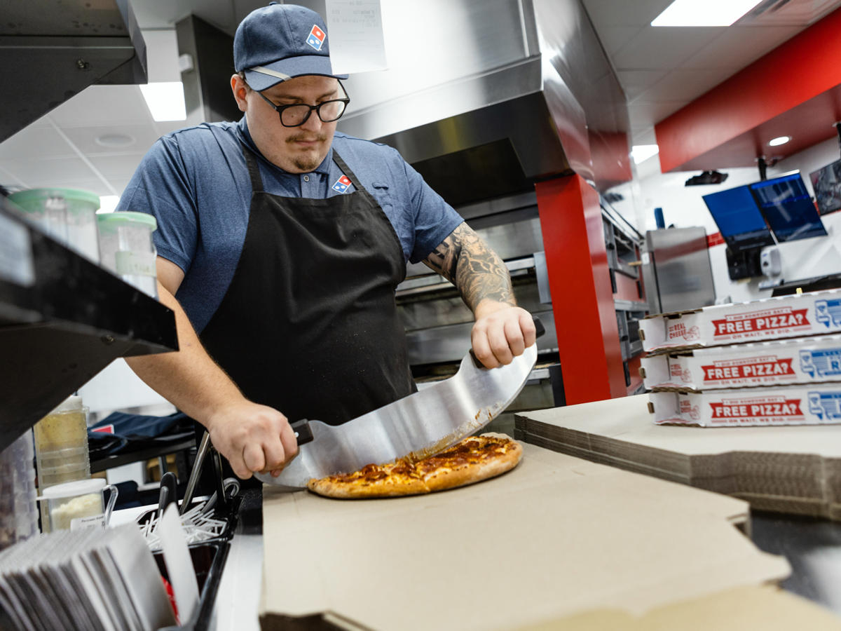 a man cutting a pizza