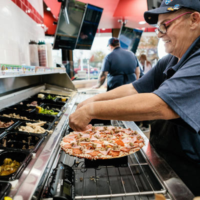 Un hombre poniendo una pizza en una sartén