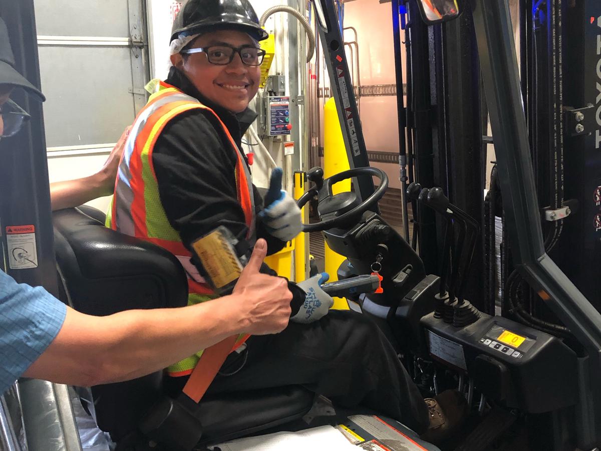 a man in a hard hat and safety vest sitting in a forklift