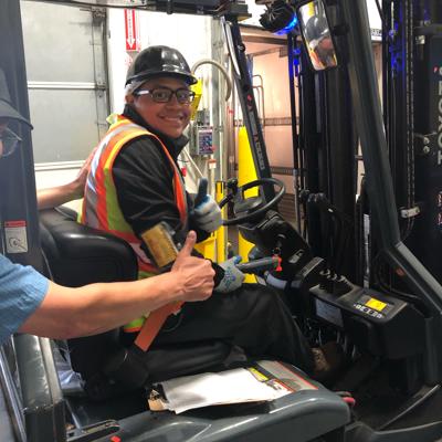 a man in a hard hat and safety vest sitting in a forklift