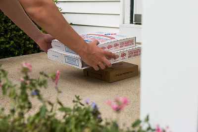 a person holding a stack of pizza boxes