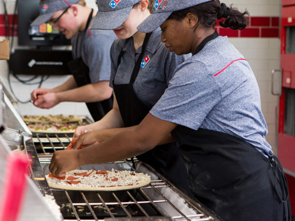 a group of people cooking pizza