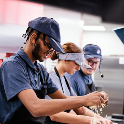 a group of people cooking pizza
