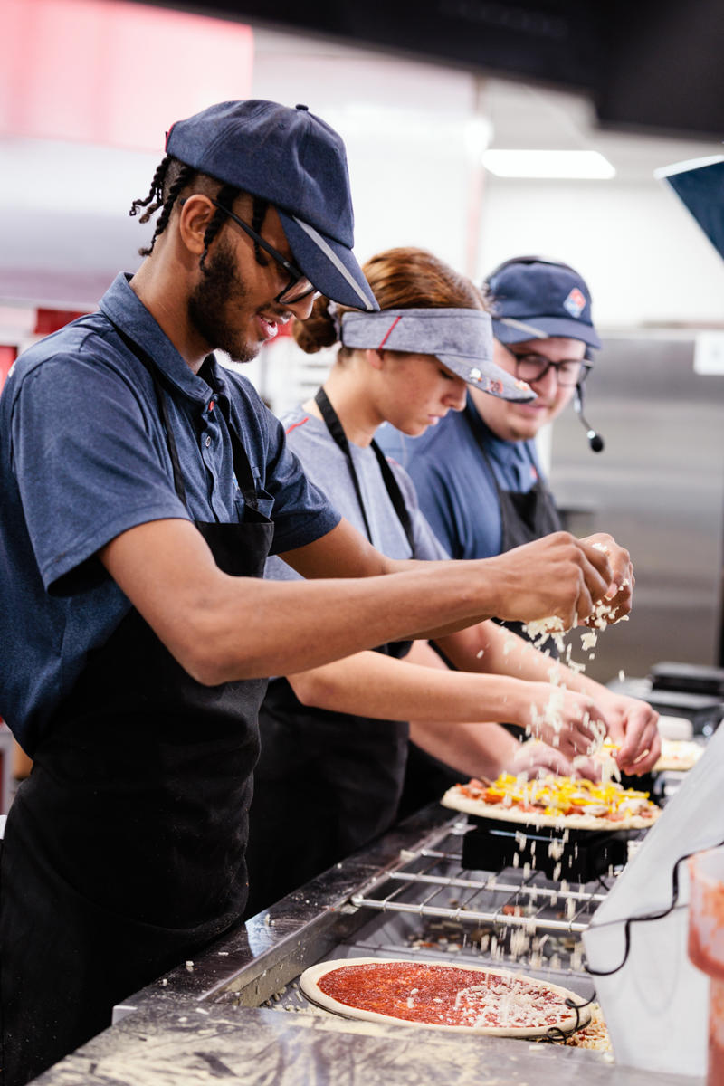 a group of people cooking pizza